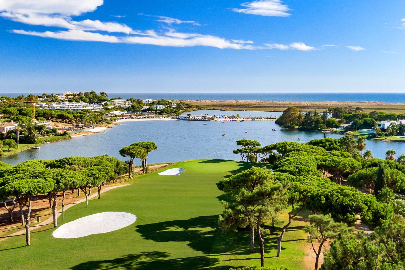 Uma vista aérea de um campo de golfe com um lago ao fundo