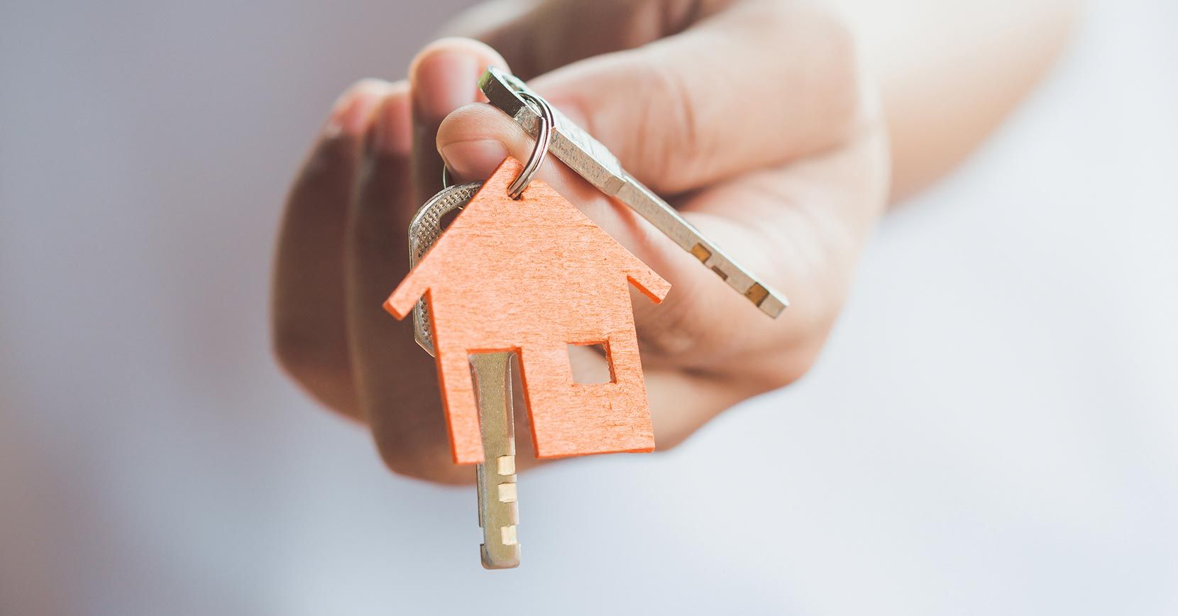 Uma pessoa está segurando uma chave de casa com um chaveiro de casa.