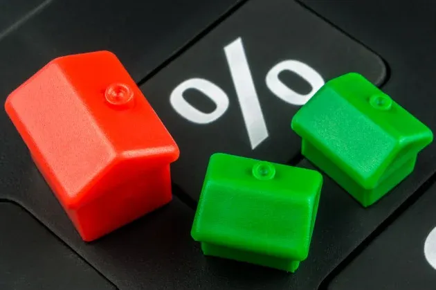 Três casas de plástico estão em cima de uma calculadora.