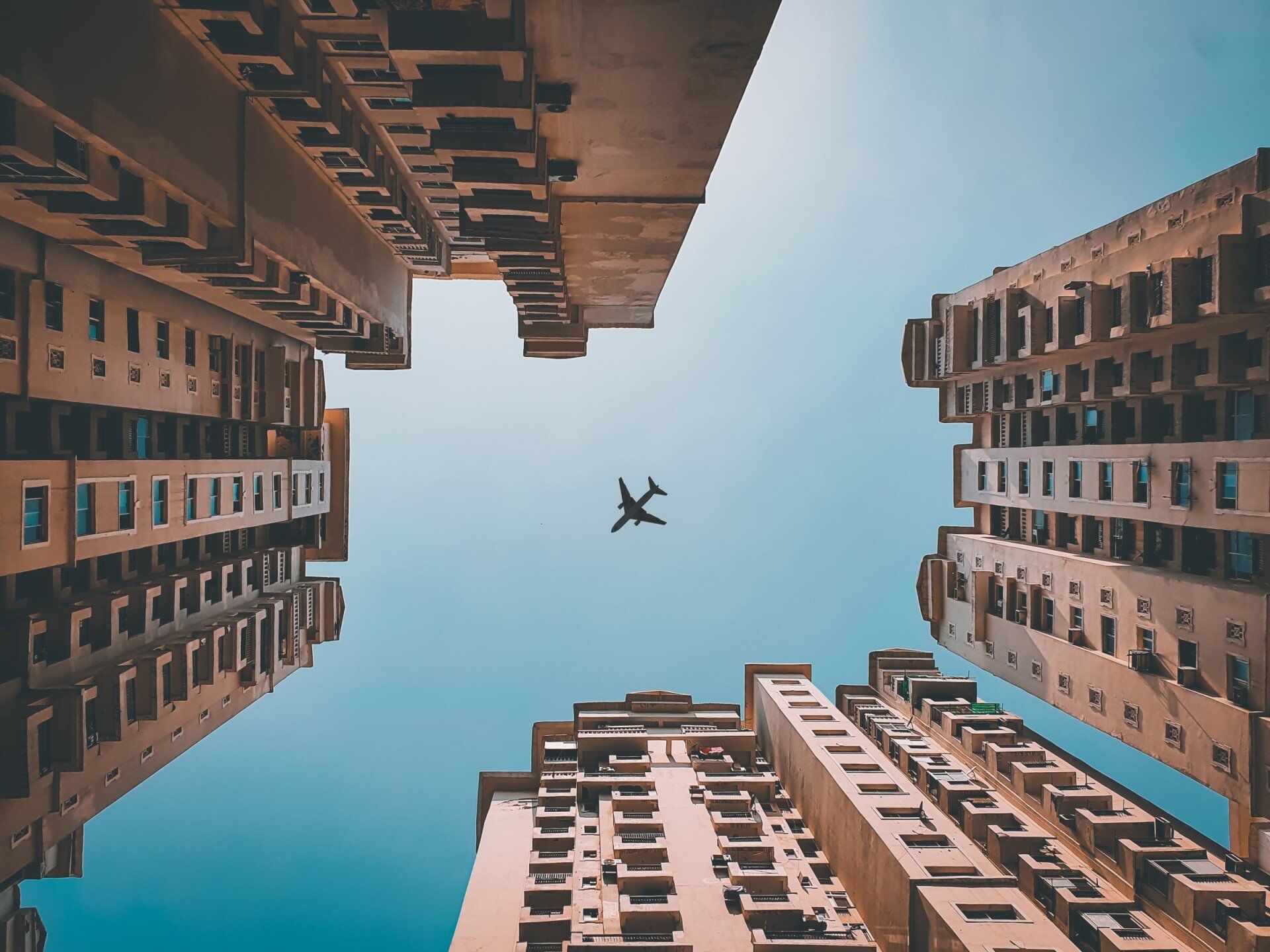 Um avião está voando no céu entre dois prédios altos.