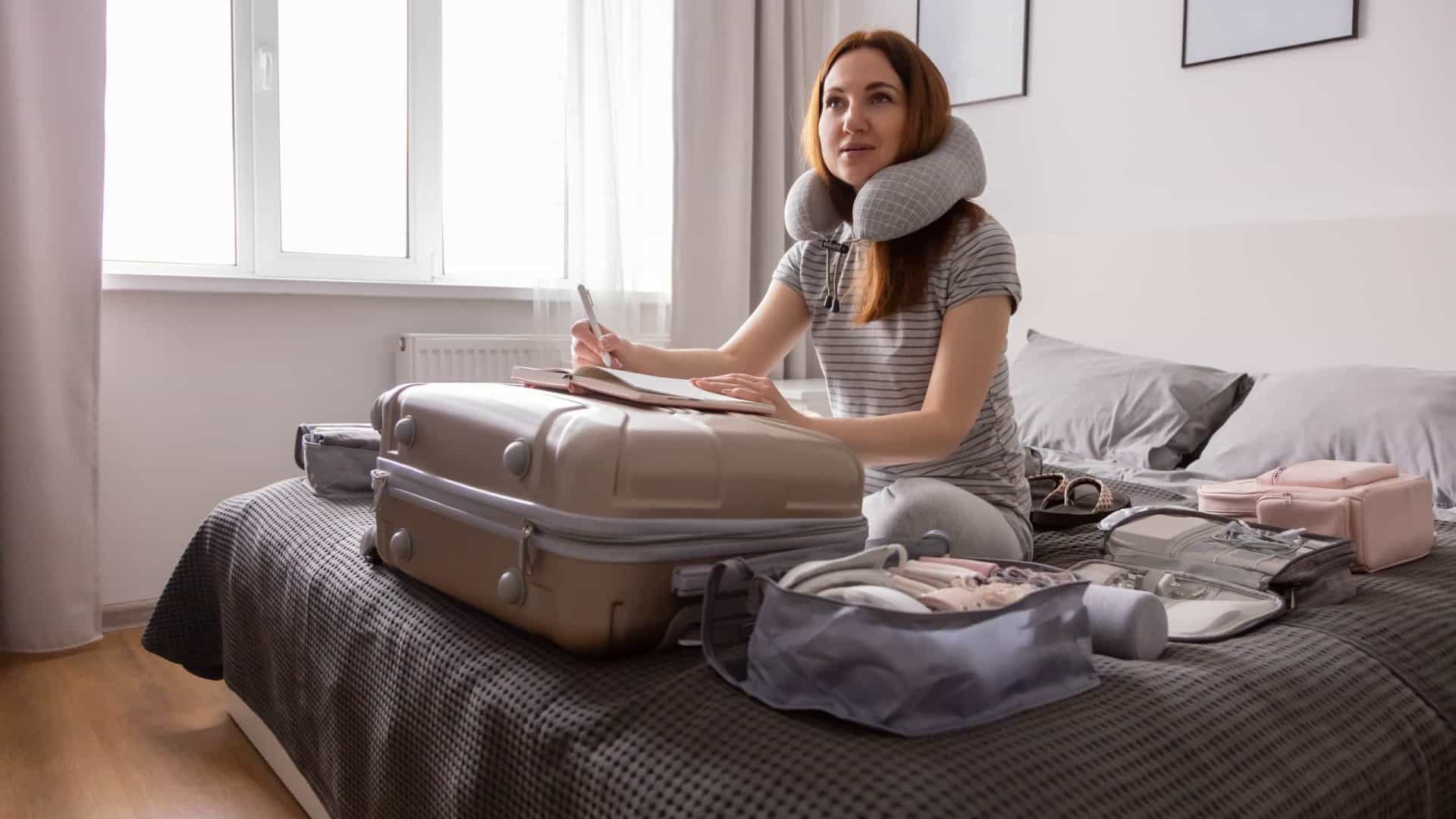 Uma mulher está sentada em uma cama com uma mala.