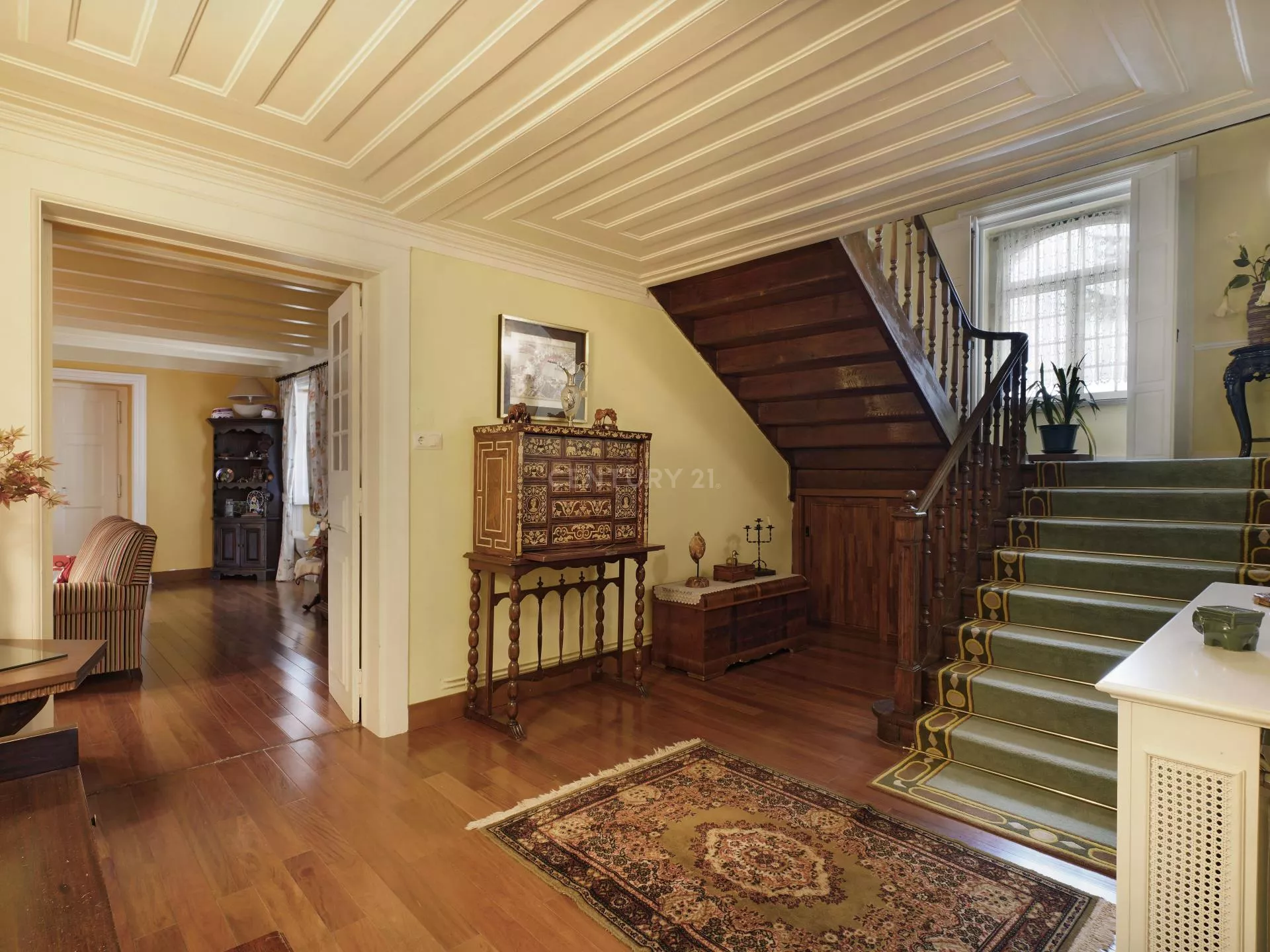 Uma sala de estar com uma escada de madeira e um tapete no chão.