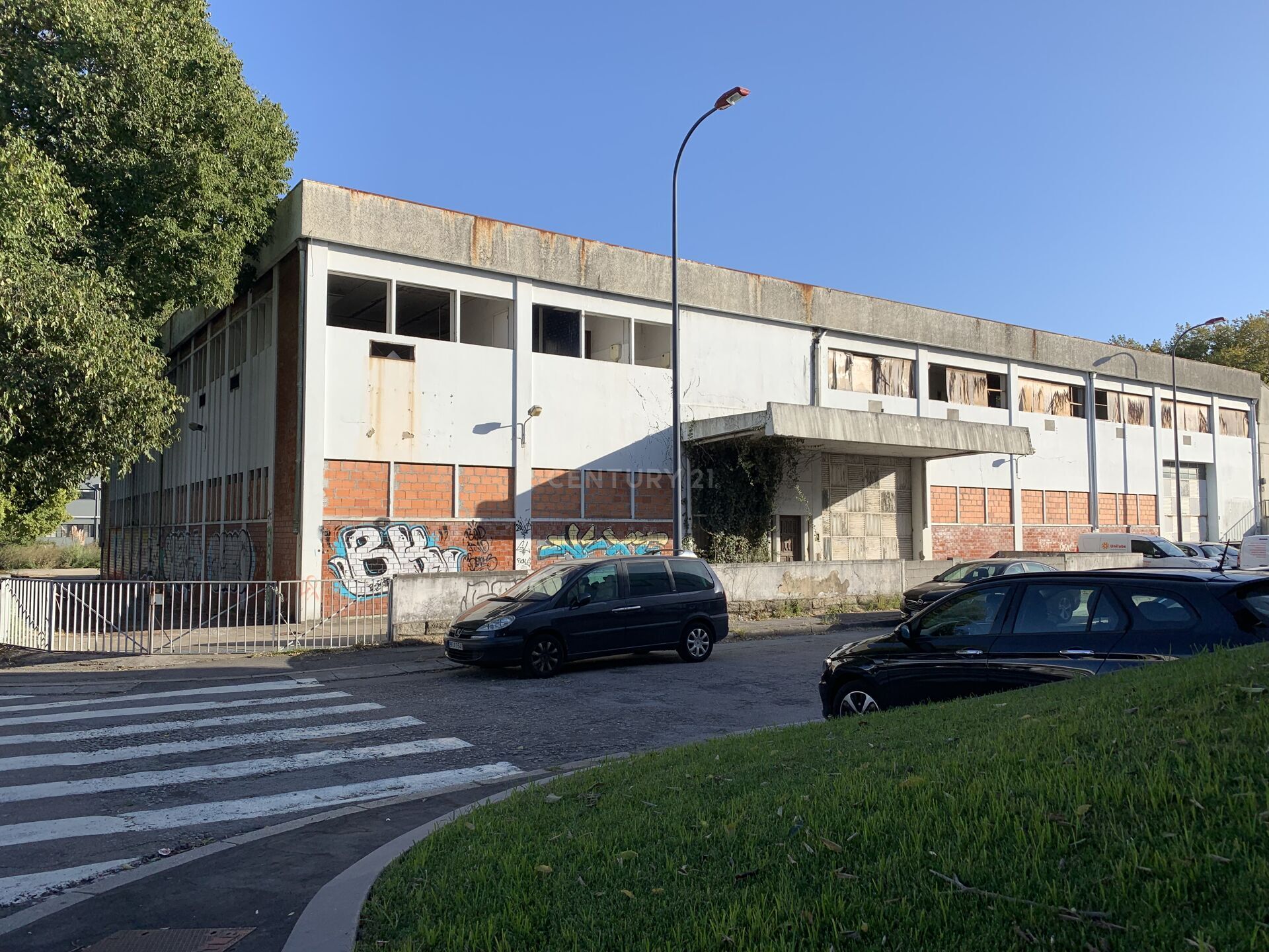 Um grande edifício com carros estacionados na frente.