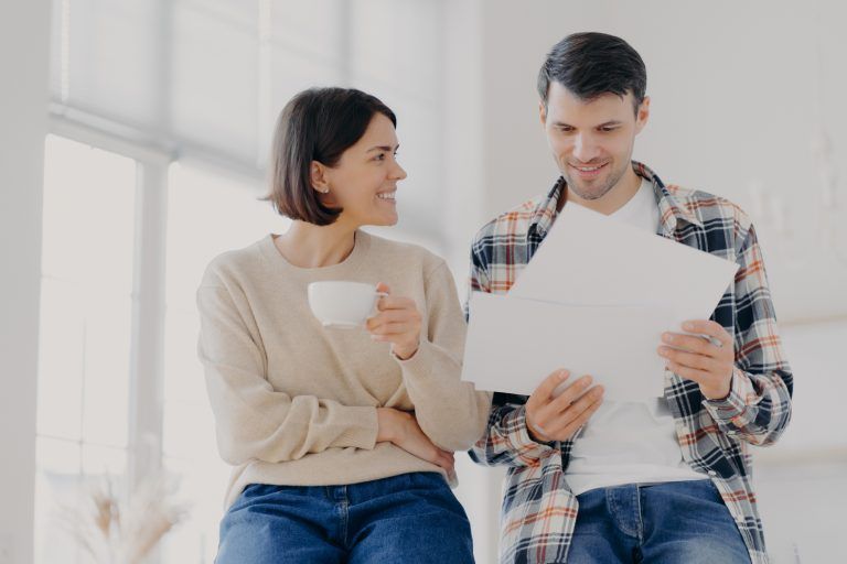 Um homem e uma mulher estão sentados um ao lado do outro olhando para um pedaço de papel.