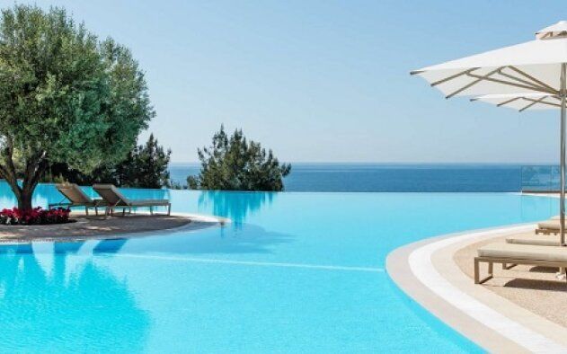Uma piscina rodeada de cadeiras e guarda-sóis com vista para o oceano