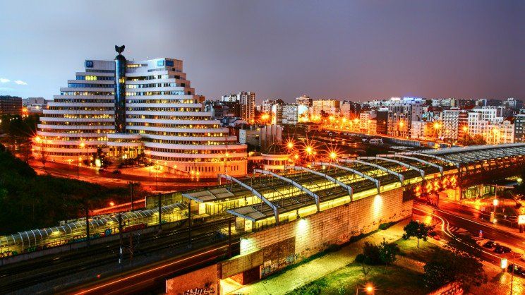 Uma vista aérea de uma cidade à noite com um trem passando por uma ponte.