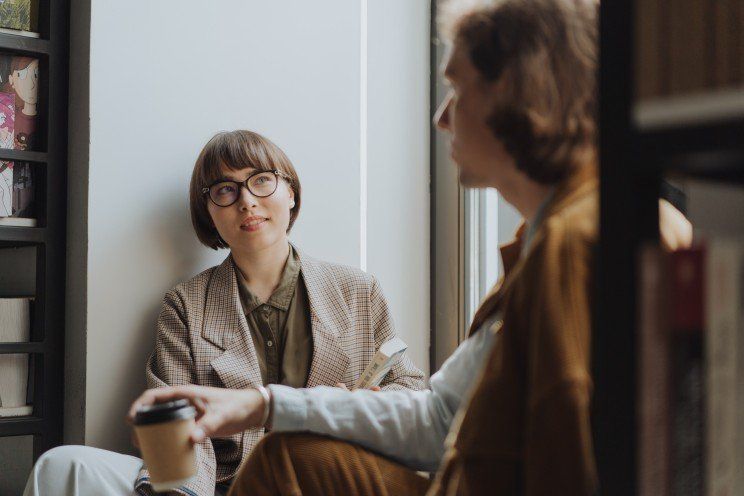 Um homem e uma mulher estão sentados no chão conversando um com o outro.