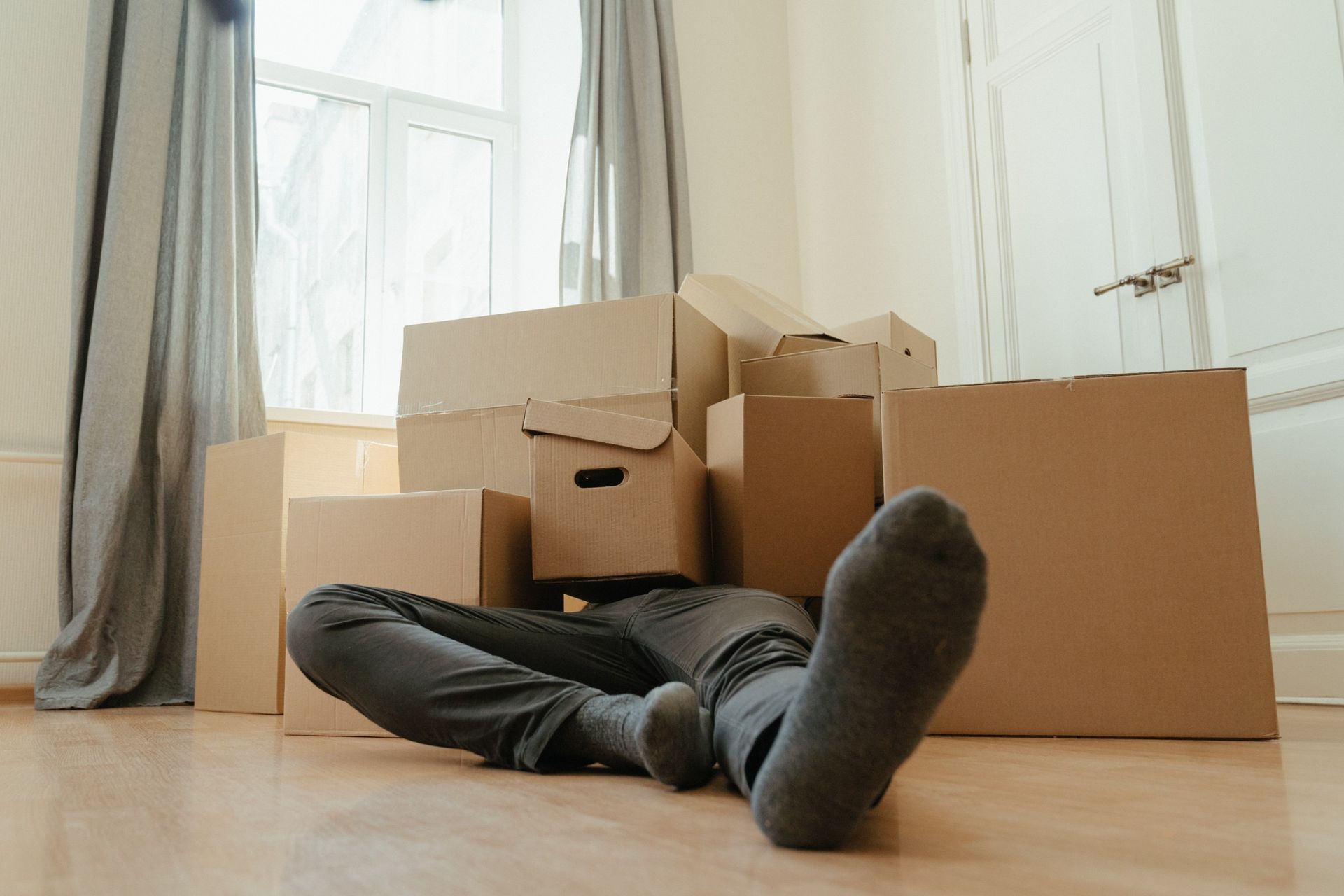 Um homem está deitado no chão em frente a uma pilha de caixas de papelão.
