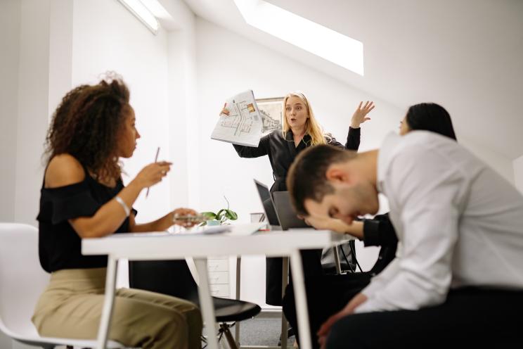 Um grupo de pessoas está sentado ao redor de uma mesa tendo uma reunião.