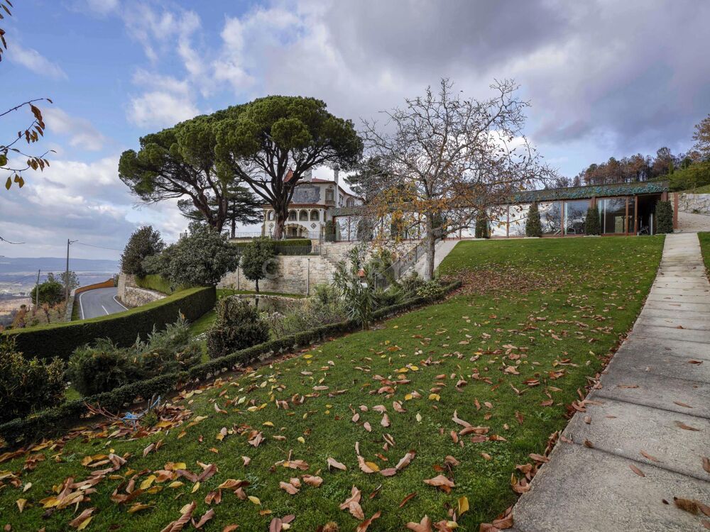 Uma casa grande fica no topo de uma colina ao lado de um campo verdejante.