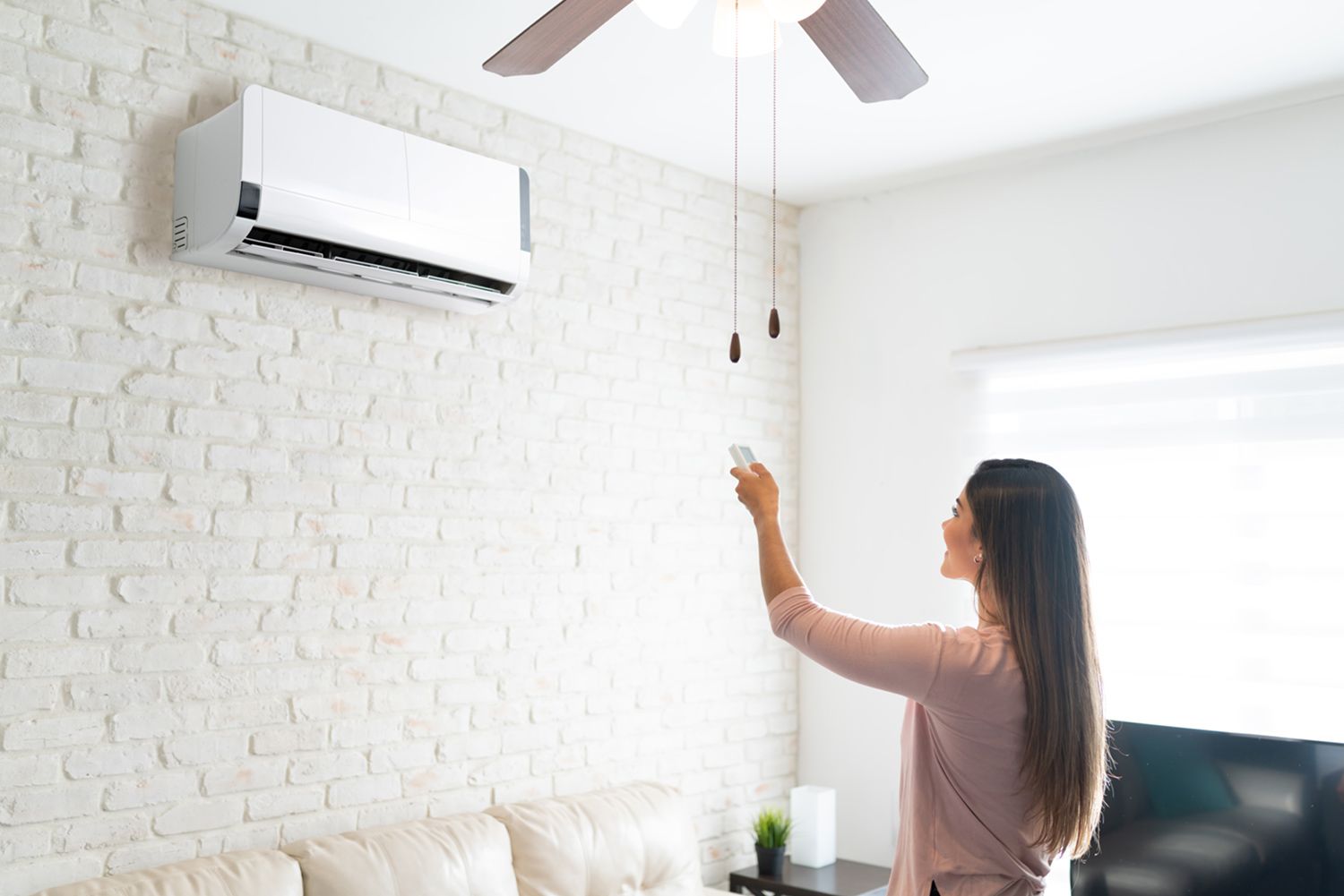 A woman is adjusting the temperature of an AC.