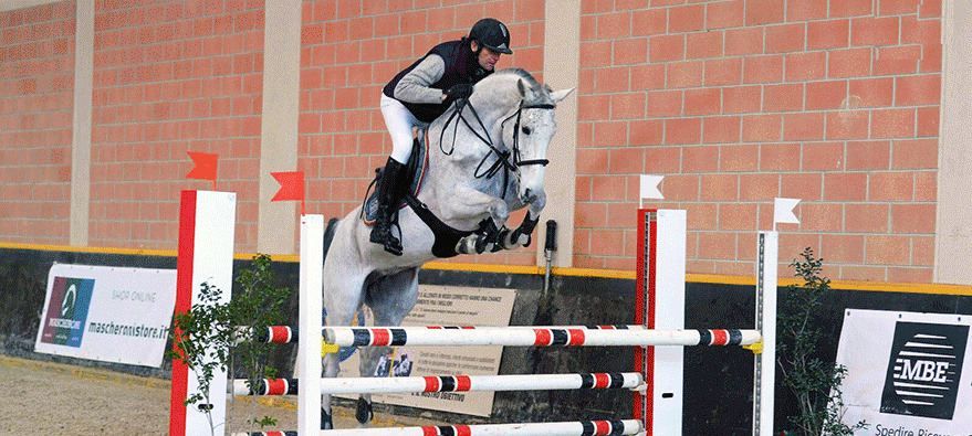 cavallo con fantino che salta ostacolo