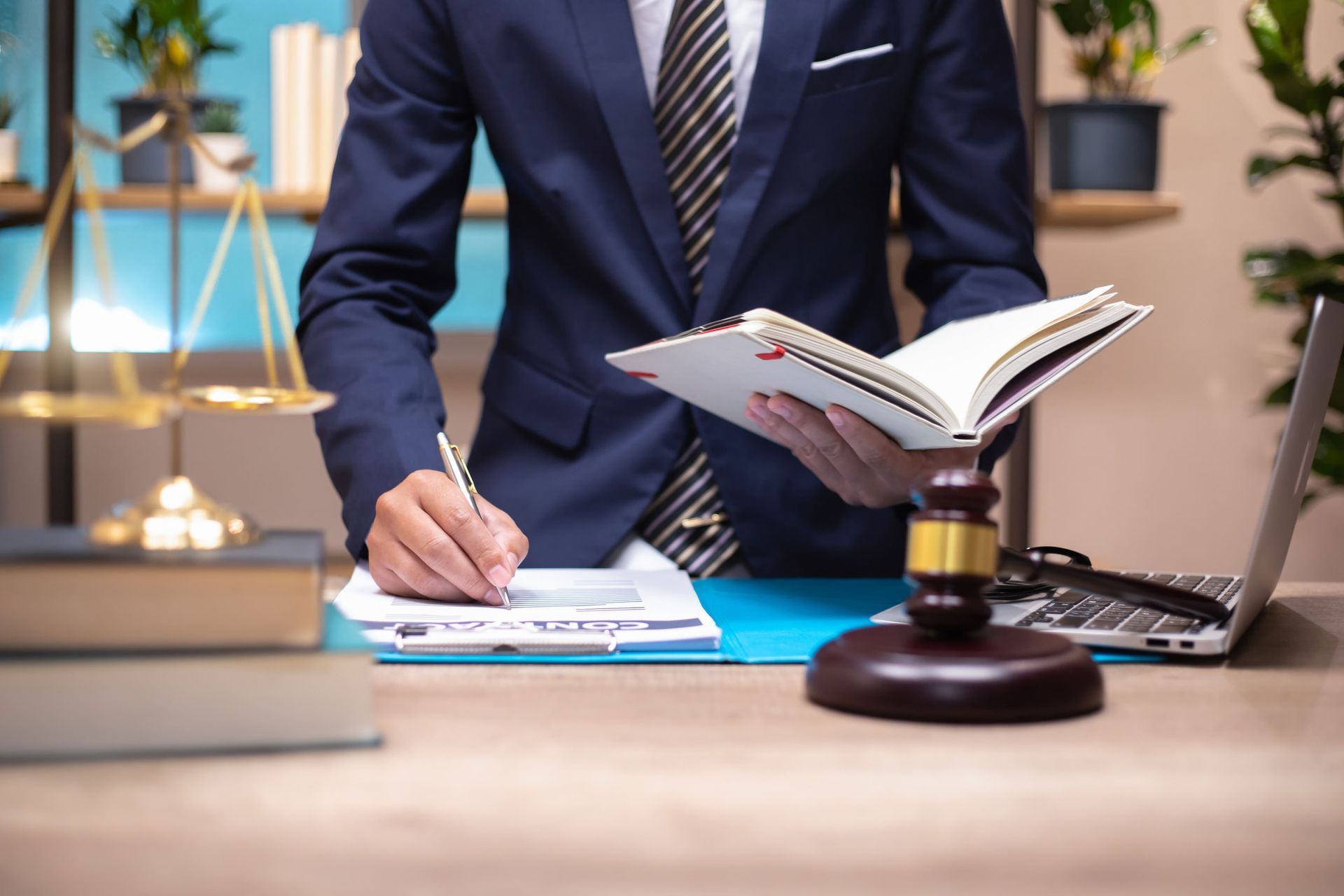 A man in a suit and tie is sitting at a desk holding a book and a clipboard.