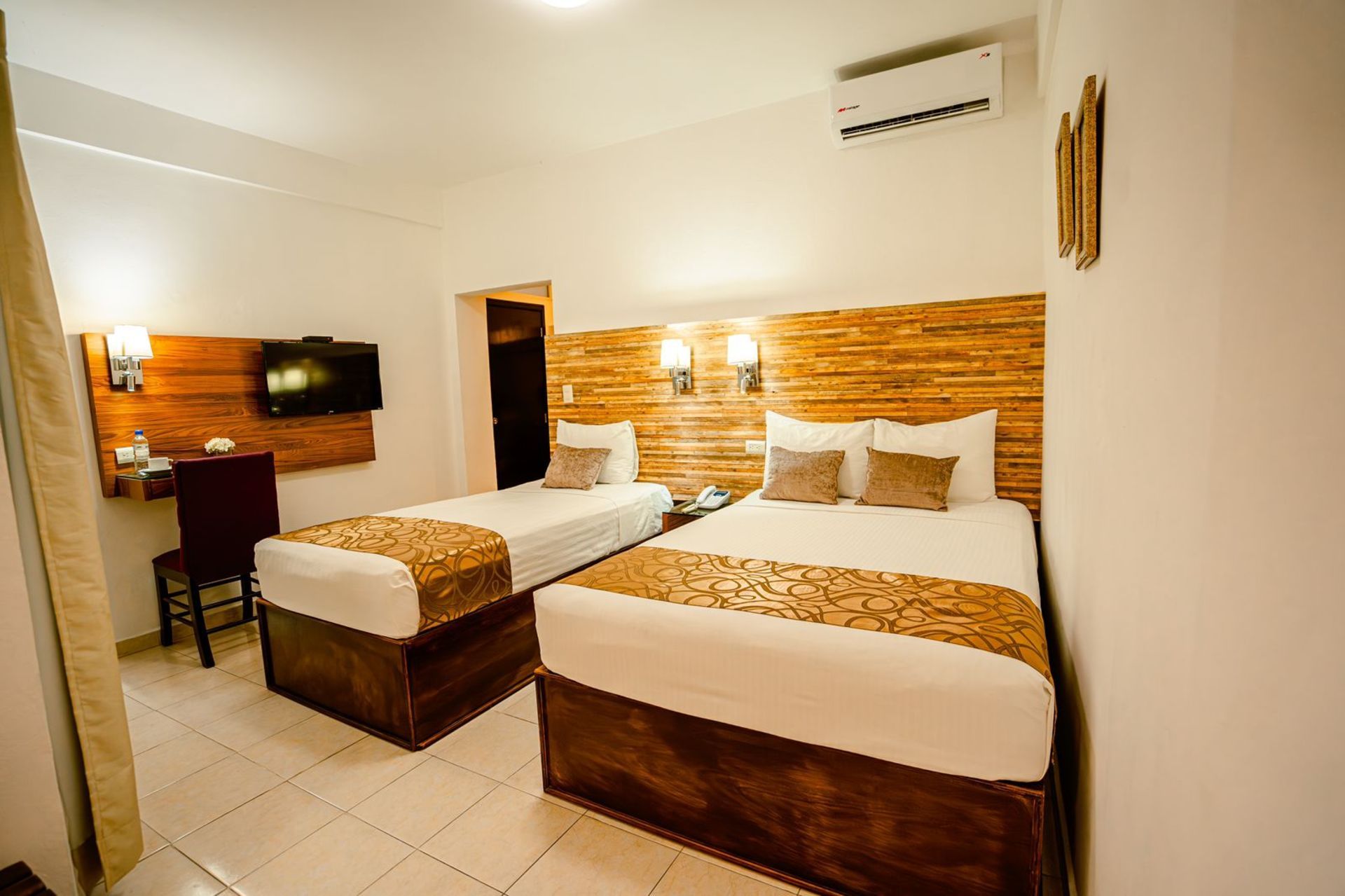 Dos camas de hotel en una habitación luminosa con detalles en madera.