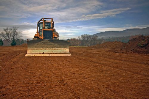 A Bulldozer Is Driving Through A Dirt Field - Millville, CA - Concrete Construction Excavating Inc.