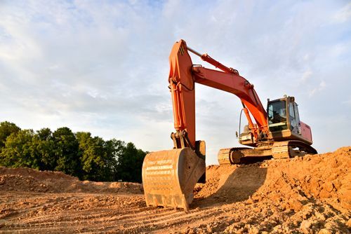 A Large Orange Excavator Is Sitting On Top Of A Pile Of Dirt - Millville, CA - Concrete Construction Excavating Inc. An excavation project underway in Redding, CA