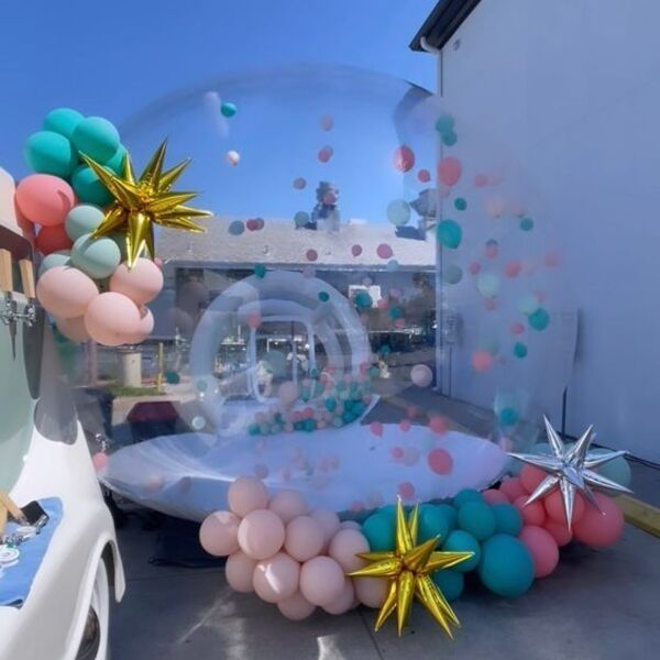 Clear balloon-decorated outdoor storefront with pastel and metallic star balloons on a sunny day