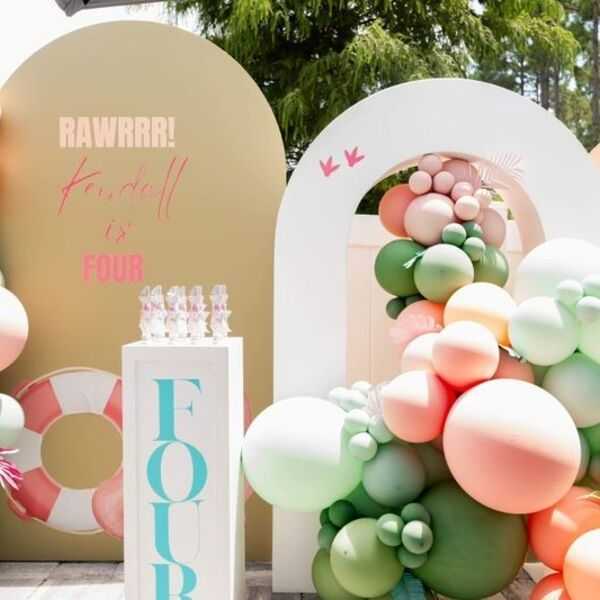 Pastel fourth birthday party backdrop with balloon arch and dessert table