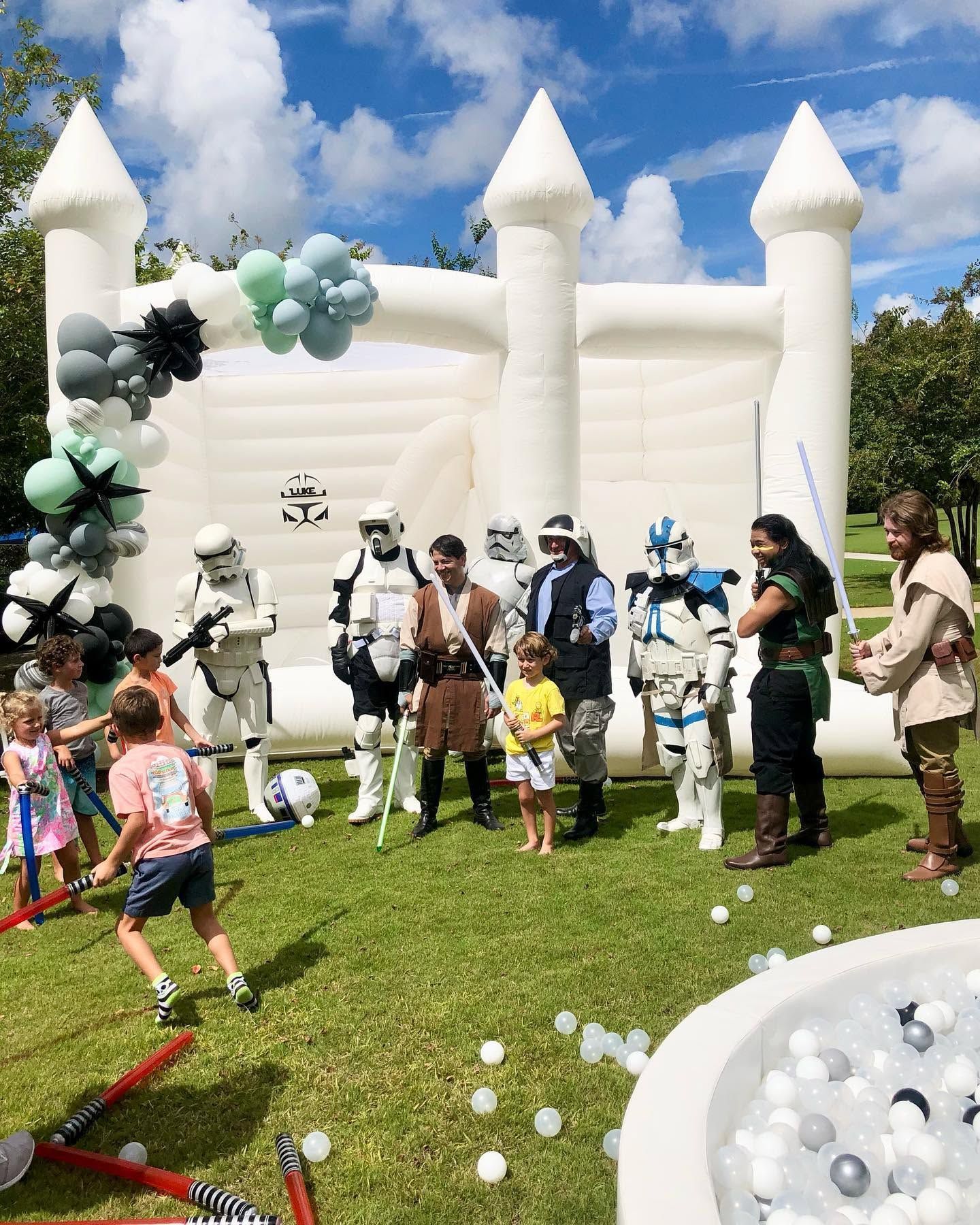 People in Star Wars costumes at an outdoor party with a white inflatable castle and bubbles