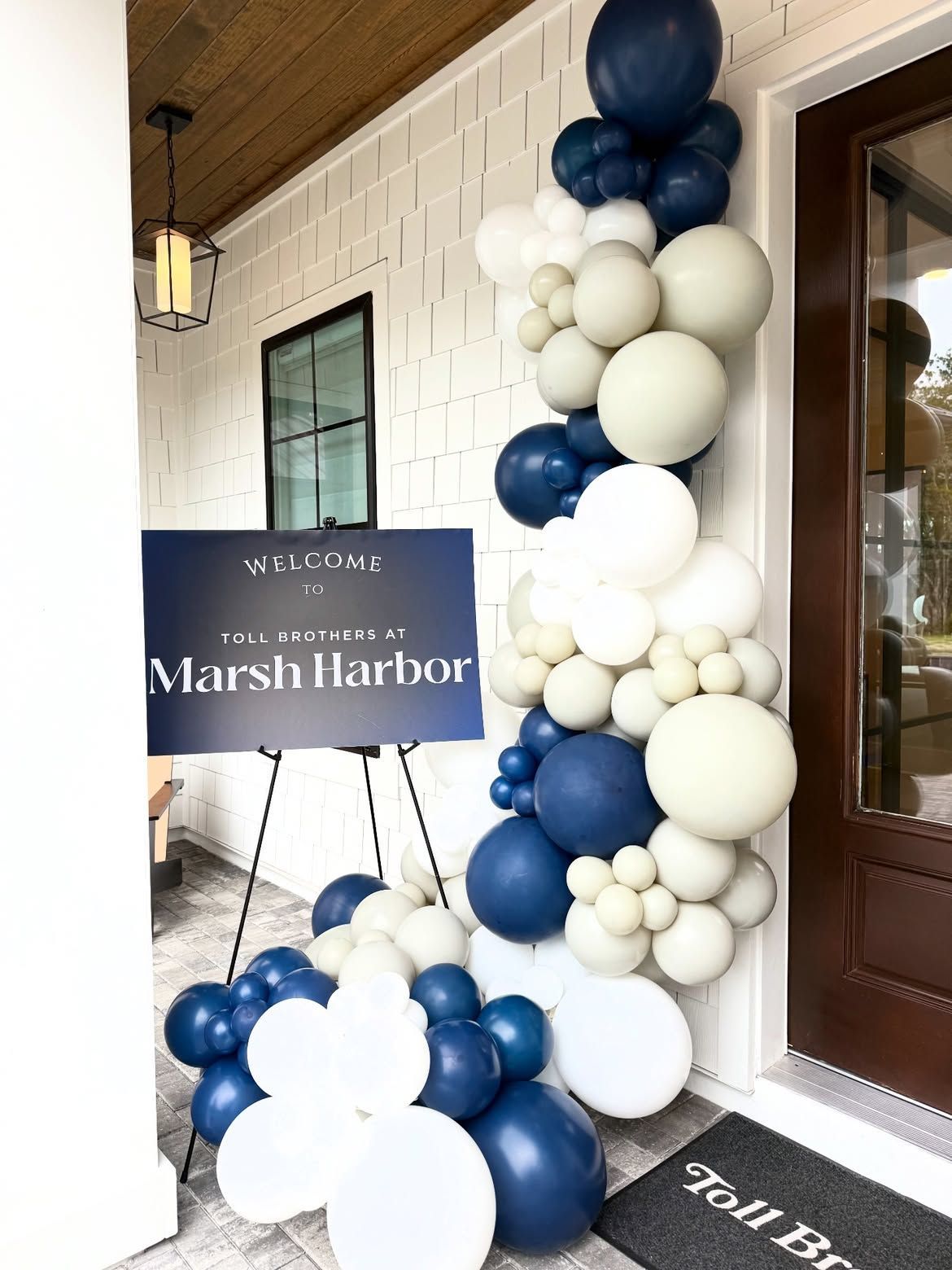Blue and white balloon arch at Marsh Harbor event entrance with sign and floor balloons