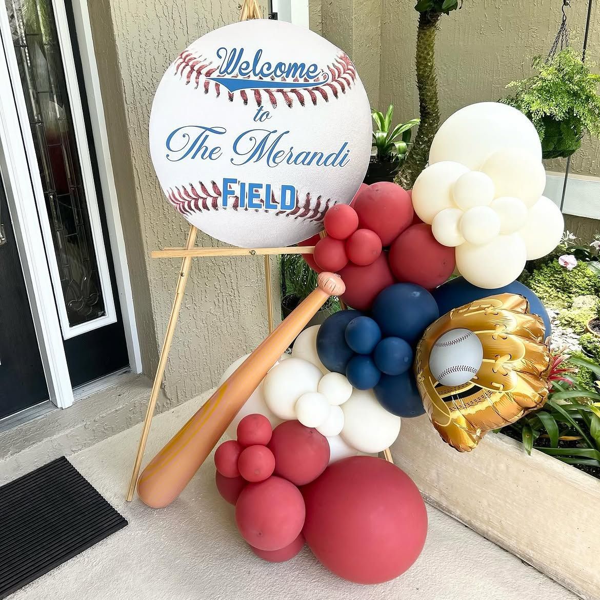 Baseball-themed balloon display with a bat, sign, and gold number 1 balloon by a doorway