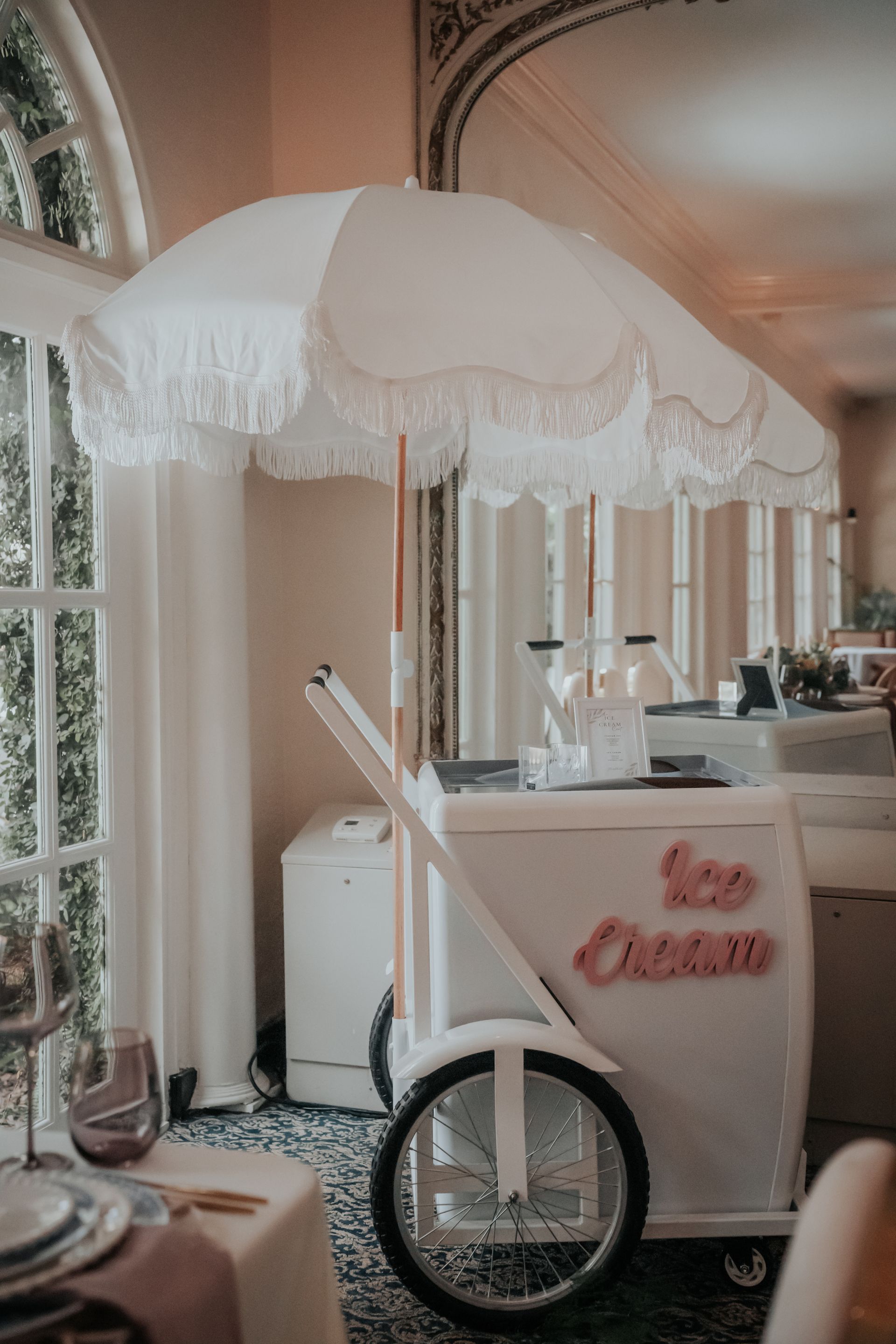 White umbrella cart with pink lettering at a decorated indoor event venue