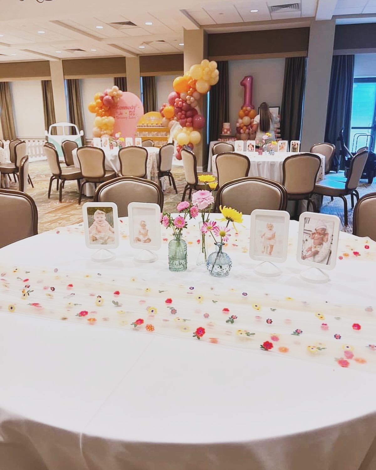 Decorated banquet table with pastel balloons and framed photos in a reception hall