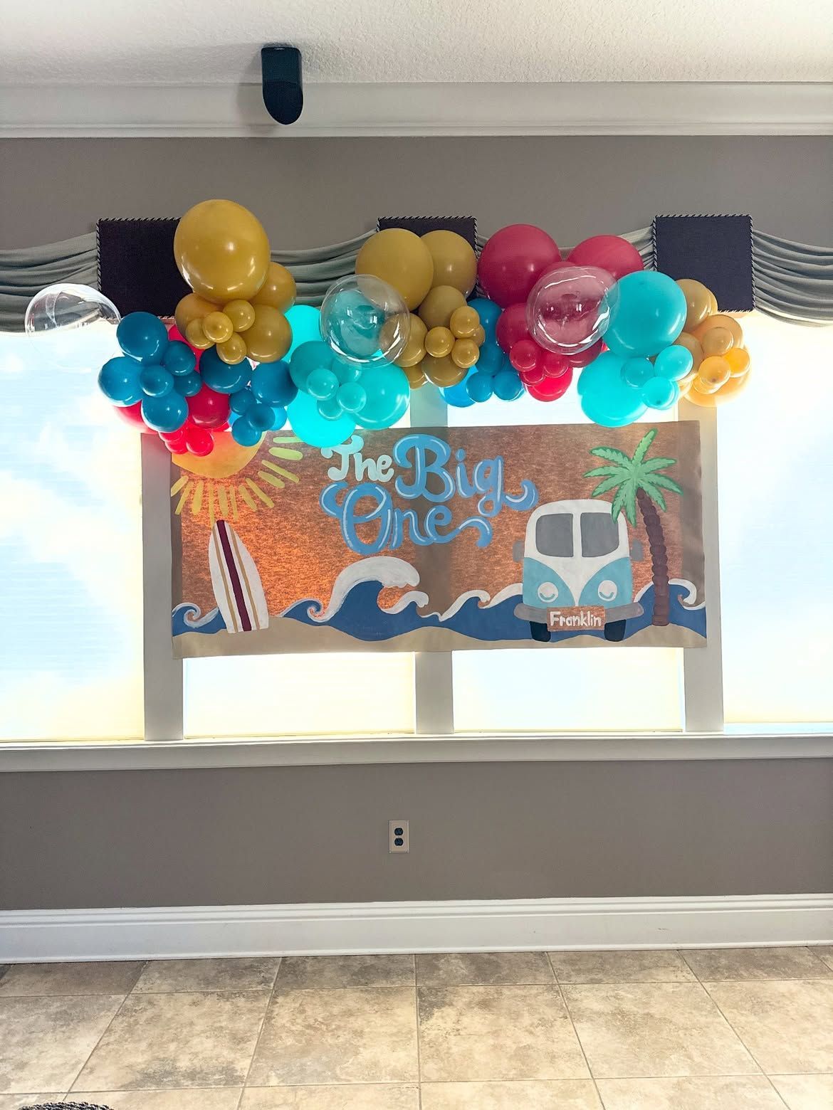 Colorful balloon garland above a “The Big One” birthday banner in a bright indoor room