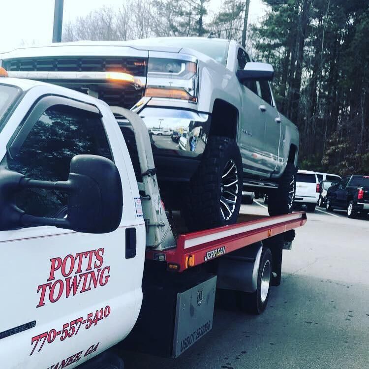 Wrecked red car and white sedan loaded on a tow truck after a crash on a wet roadside