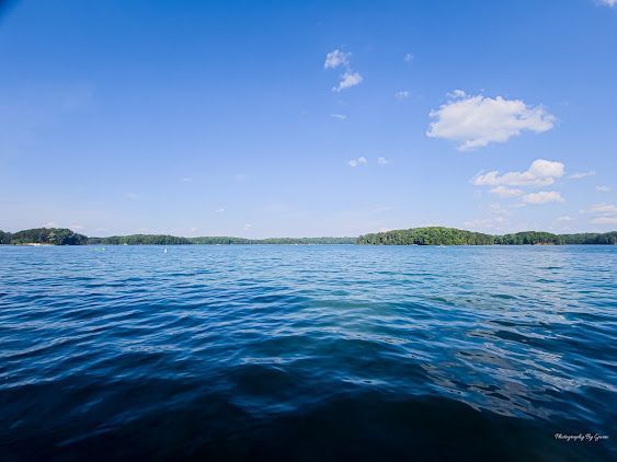 Blue ocean water under a bright sky with scattered clouds and distant green islands
