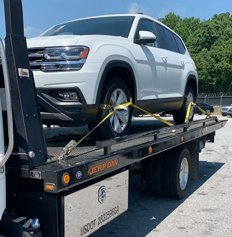 Wrecked red car and white sedan loaded on a tow truck after a crash on a wet roadside