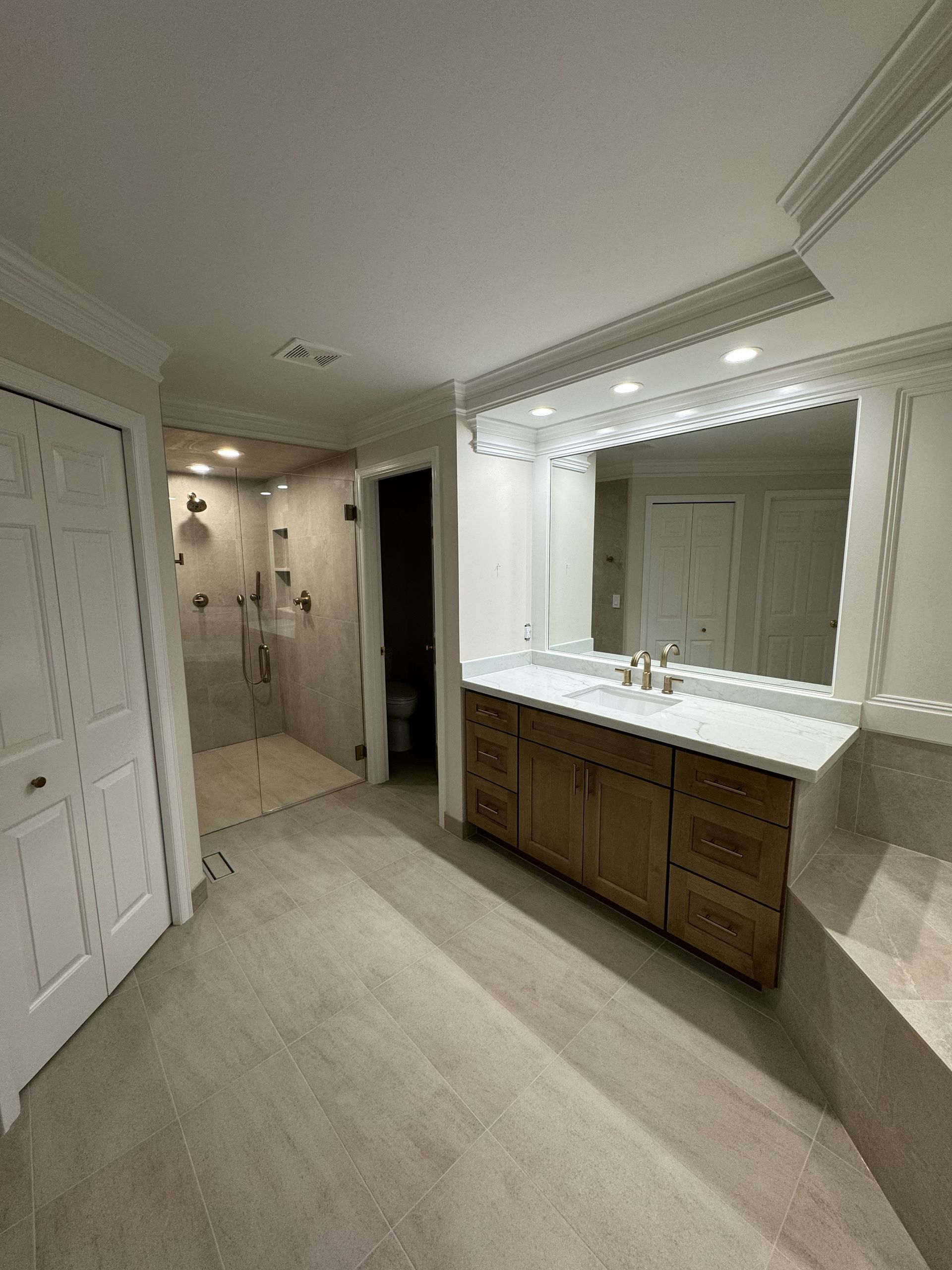 Spacious bathroom vanity area with double sinks, large mirror, and beige carpet flooring.
