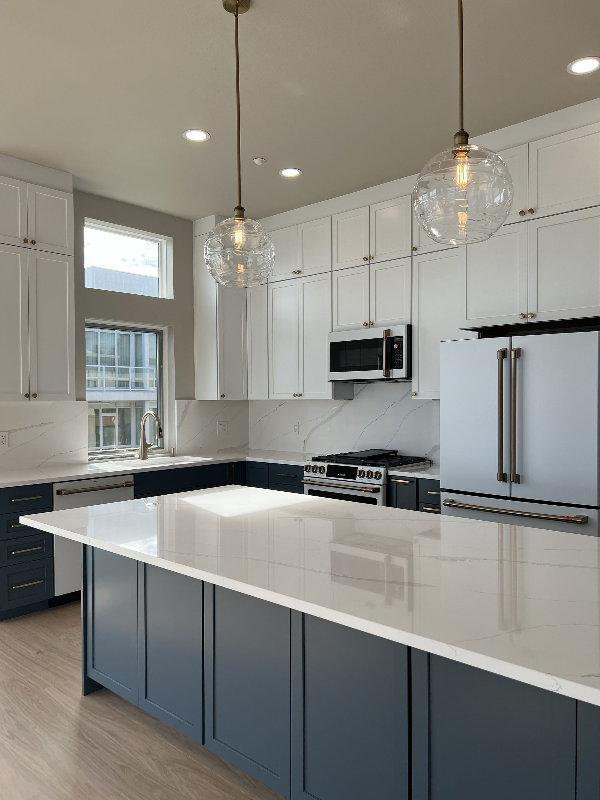 Bright modern kitchen with white cabinets, large island, and pendant lights