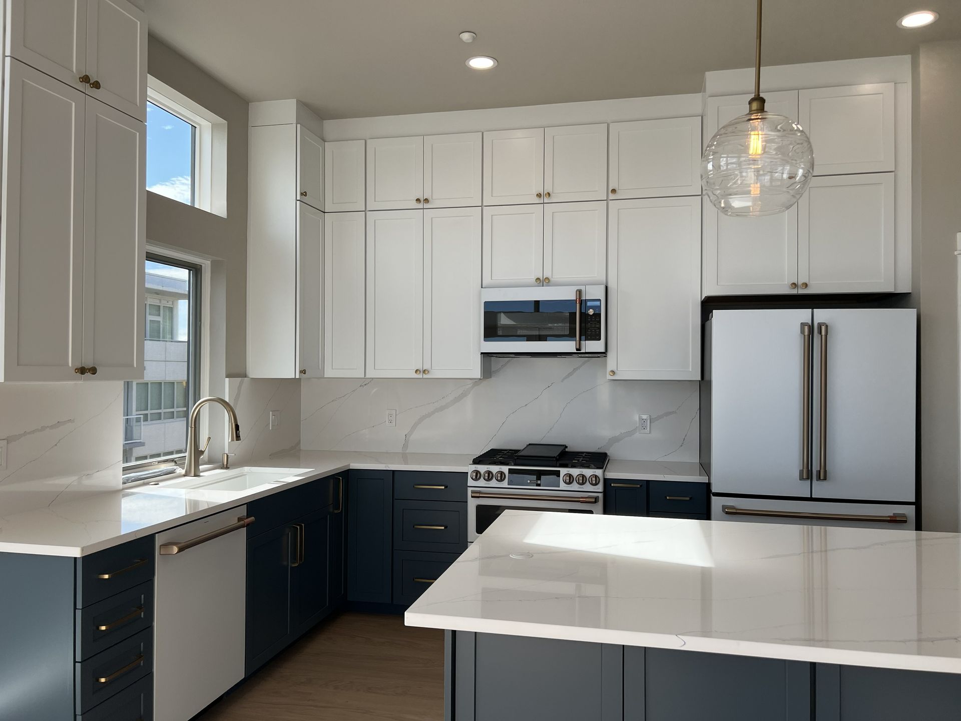 Modern white kitchen with navy lower cabinets, stainless appliances, and a large island
