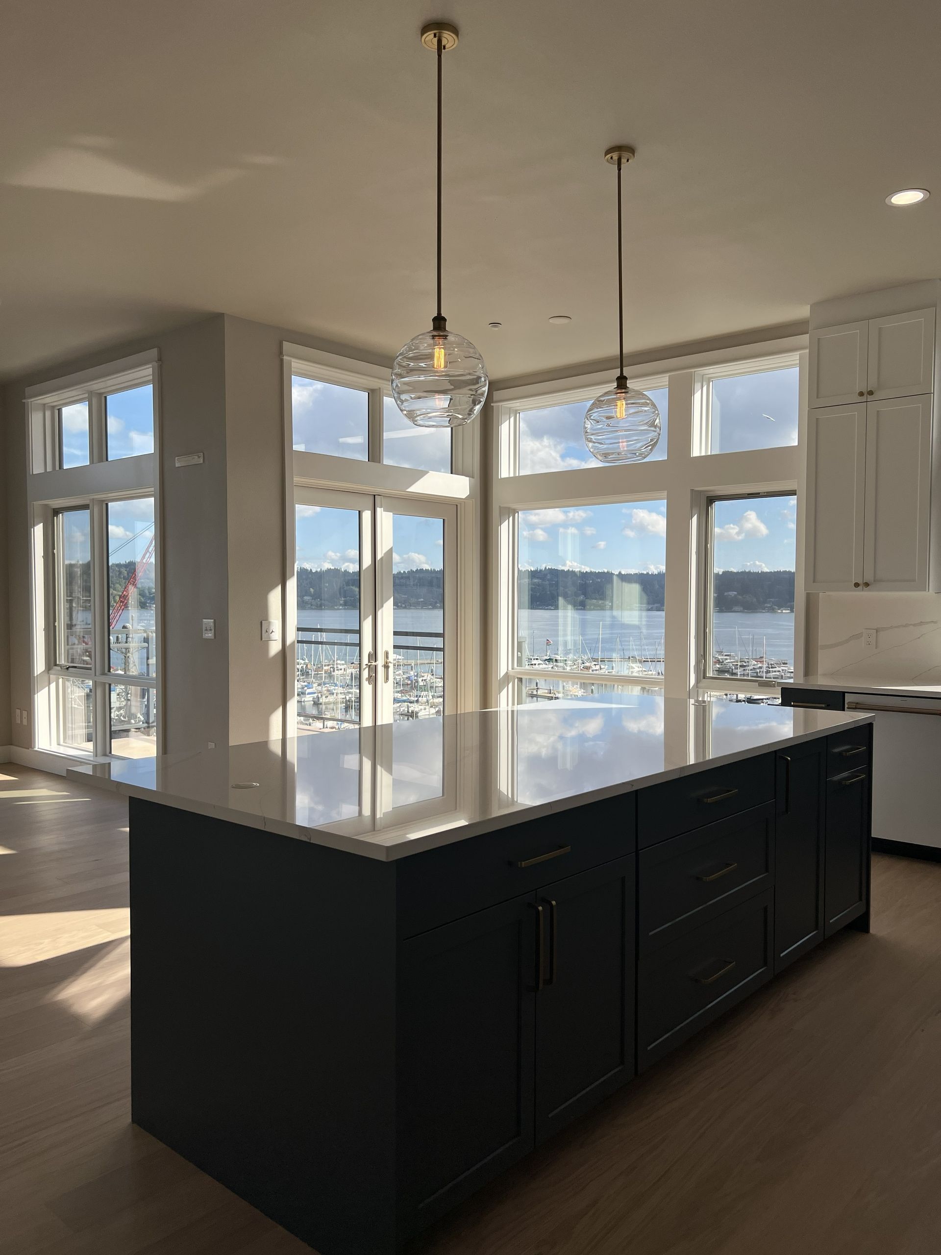 Modern kitchen with dark island, pendant lights, and large windows overlooking water