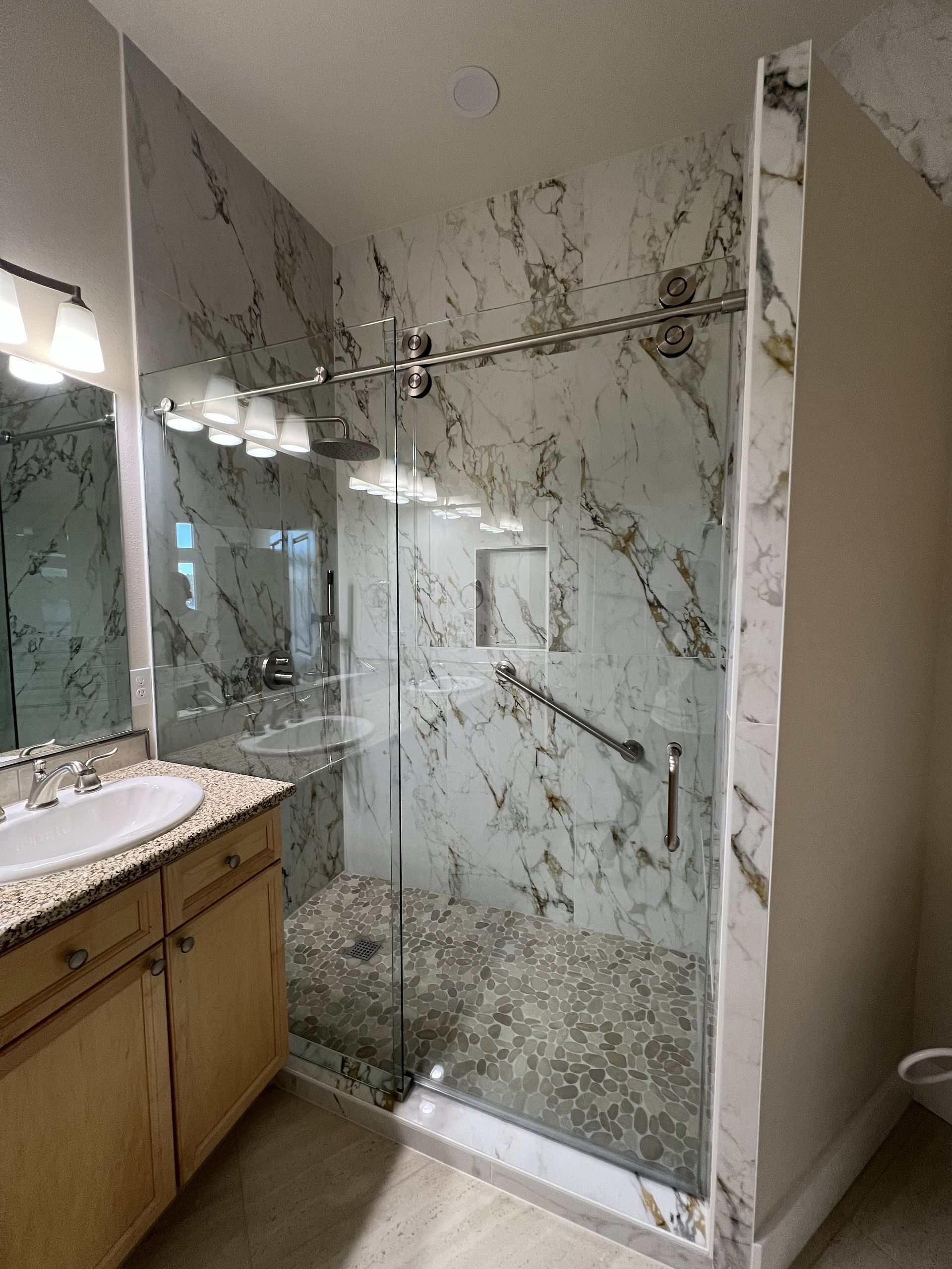 Bathroom with a glass-enclosed shower, marble-pattern tile, and vanity sink.