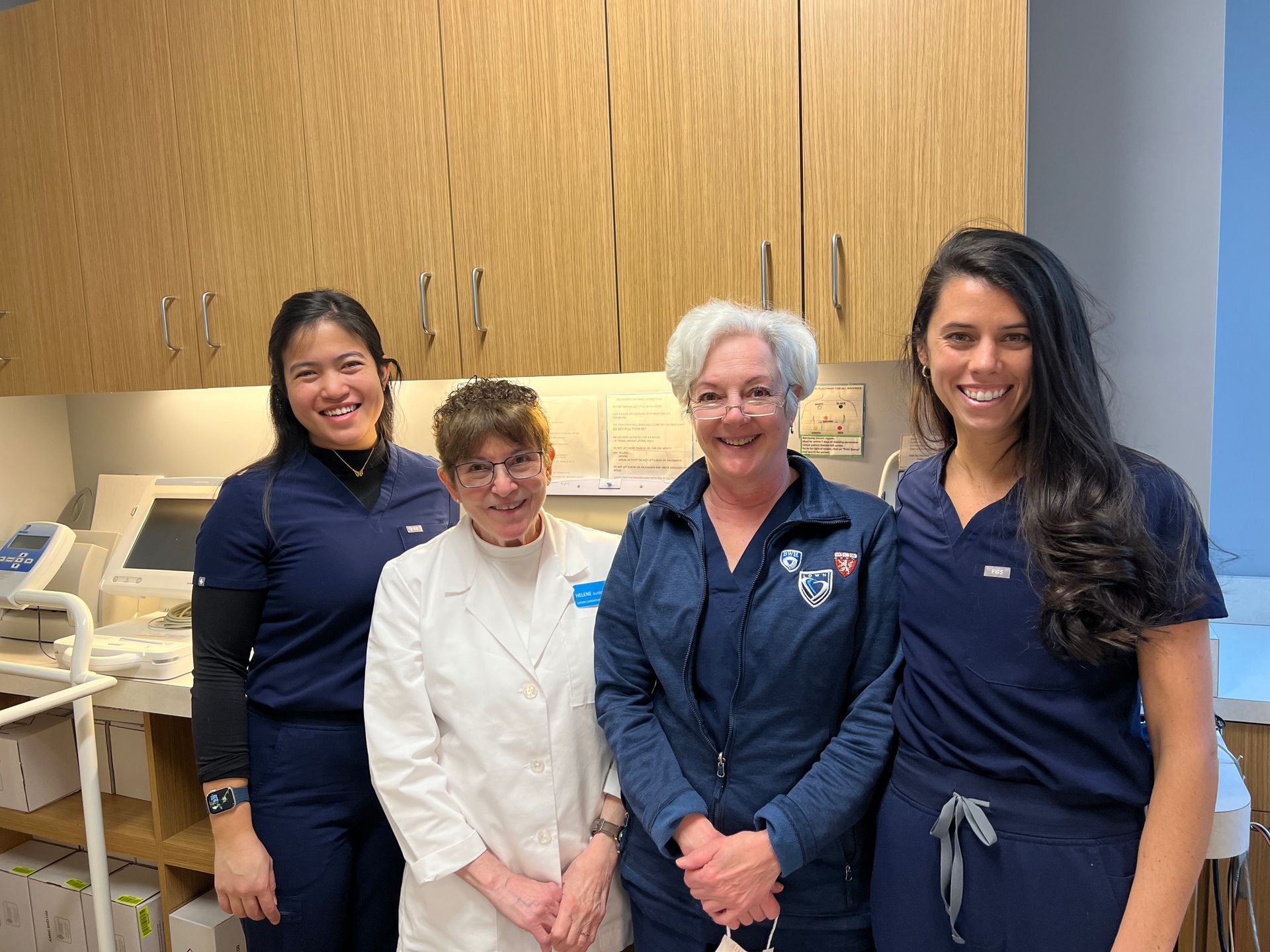 A group of nurses are posing for a picture in a hospital room.