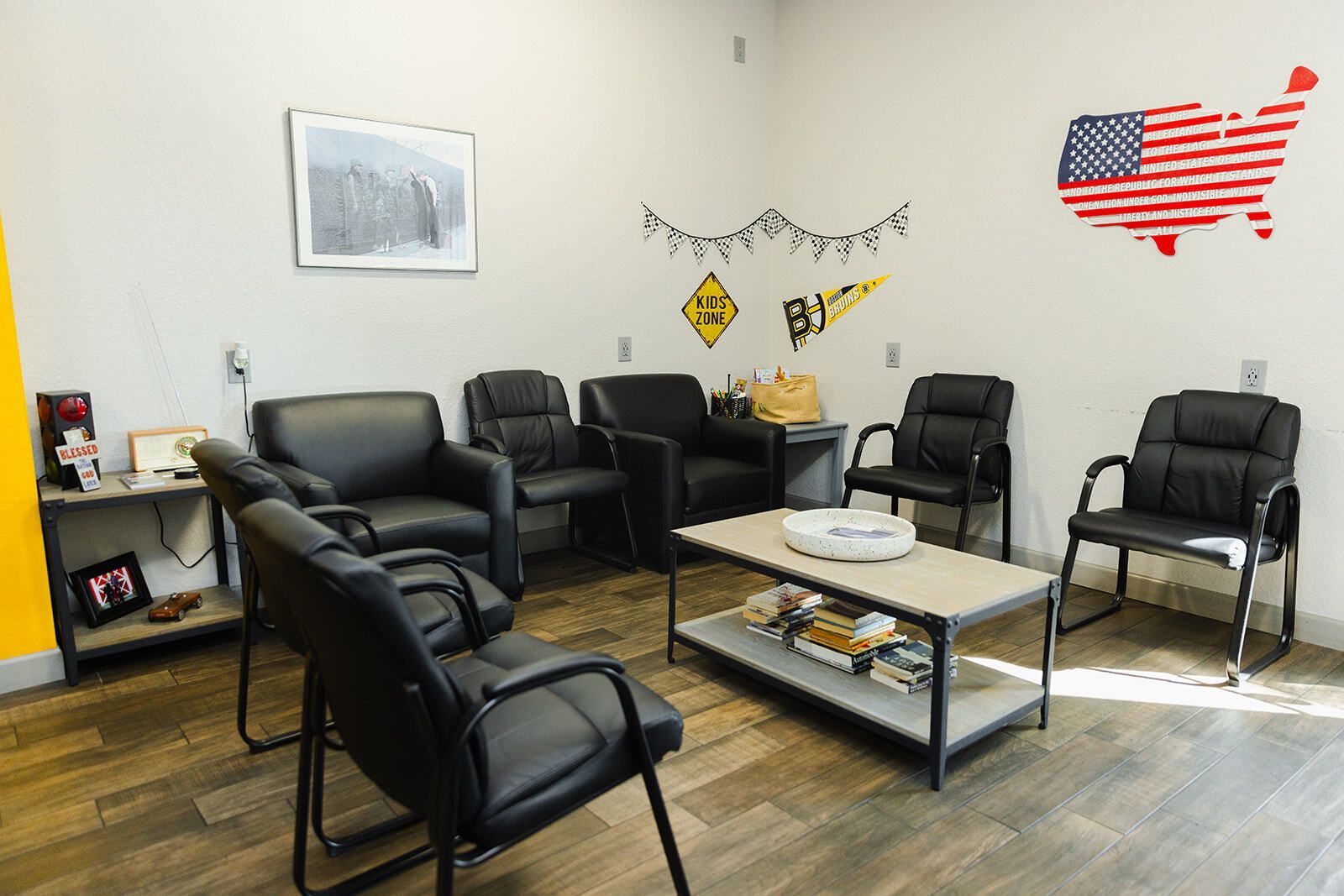 Waiting room with black chairs, coffee table, and patriotic wall decor. | Marcos Auto Service