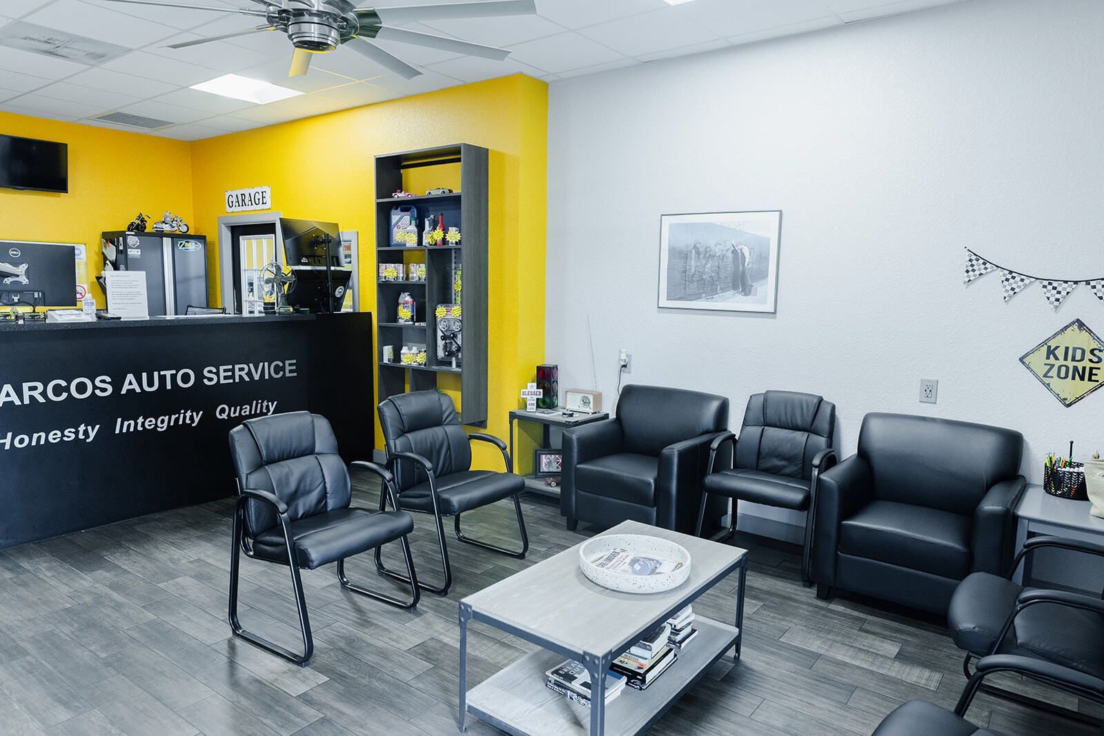 Waiting room with black chairs and a coffee station, yellow and white walls. | Marcos Auto Service
