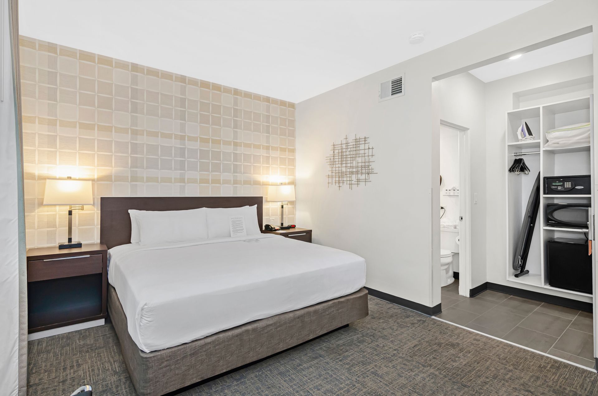 King guest room at Ohio House Motel Chicago featuring plush bed, bedside lighting and open closet with mini fridge