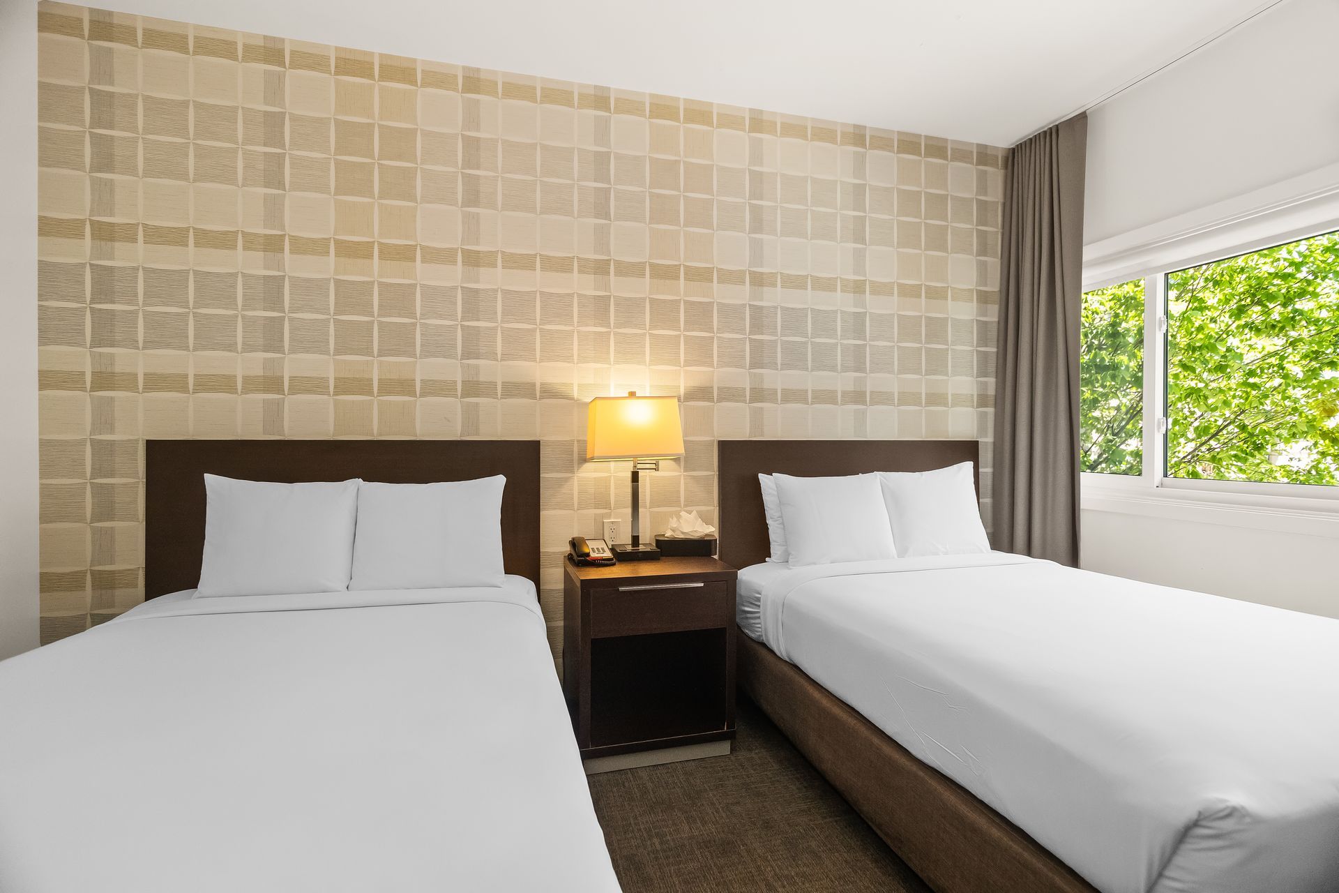 Spacious hotel guest room with two beds, open closet area, and contemporary design