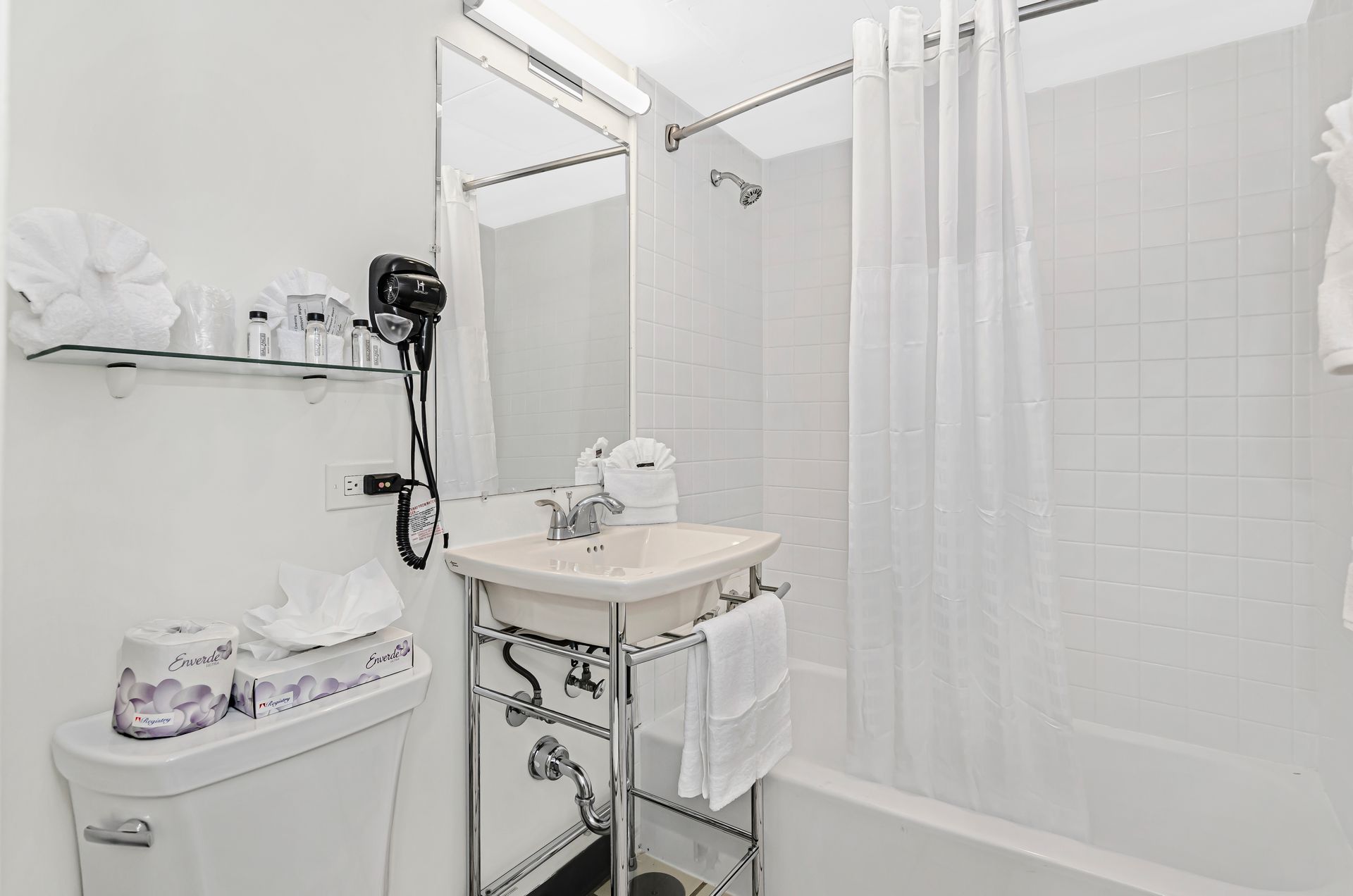 Clean guest bathroom at Ohio House Motel Chicago with bathtub, shower curtain, vanity and fresh towels