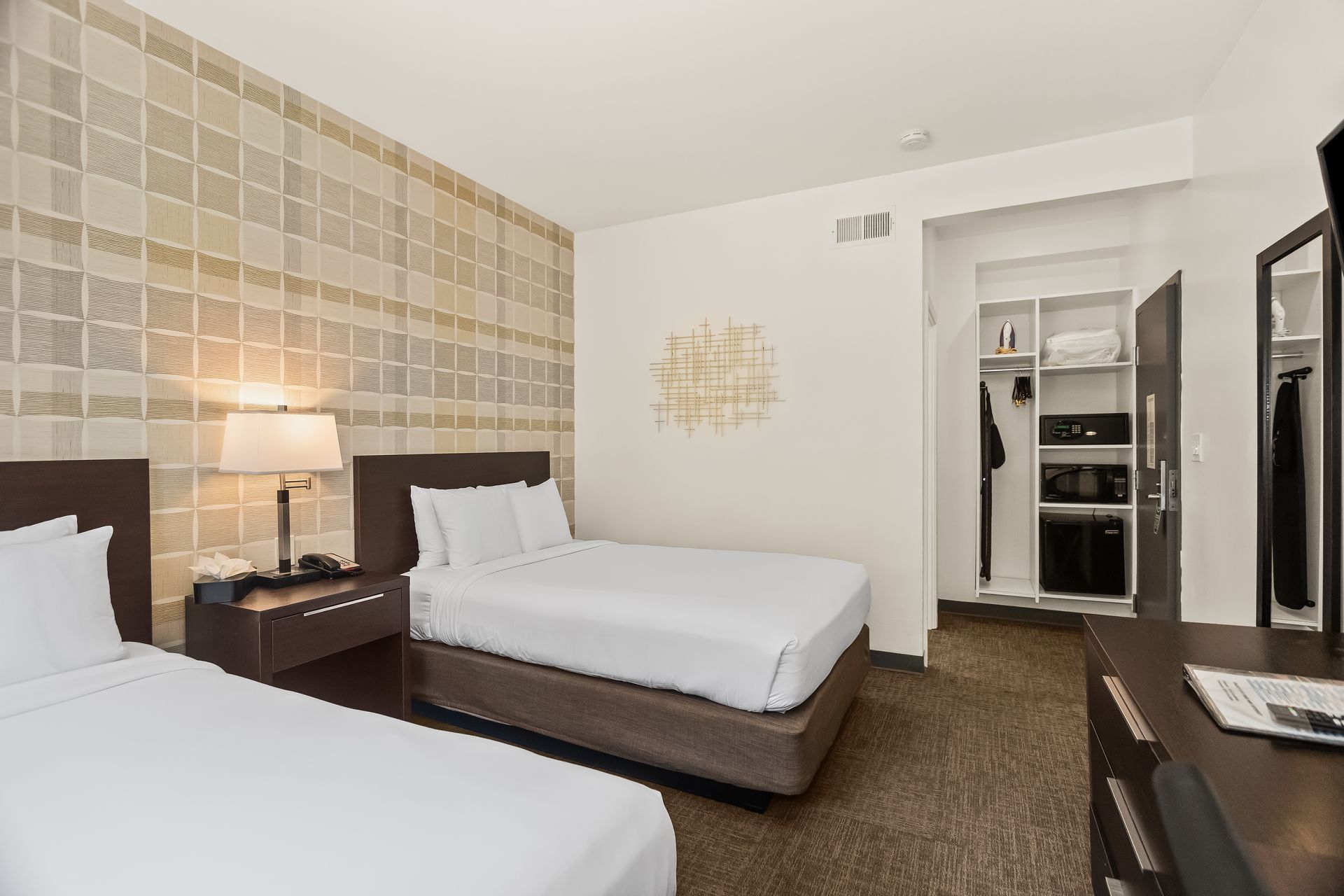 Modern hotel guest room with queen bed, warm lighting, and contemporary decor