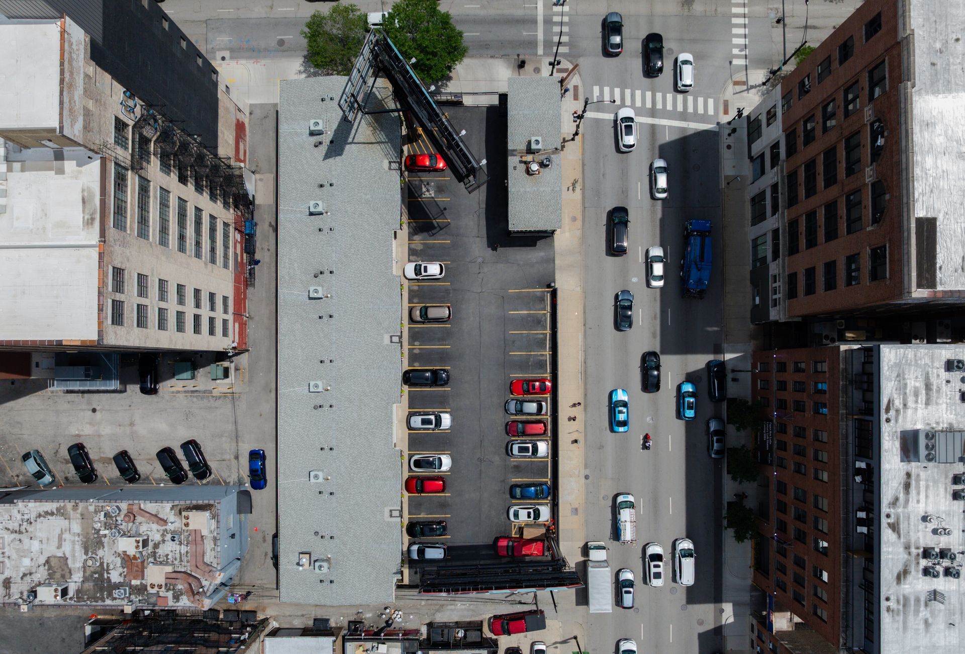 Aerial view of a city block with parked cars, a street, and surrounding buildings.