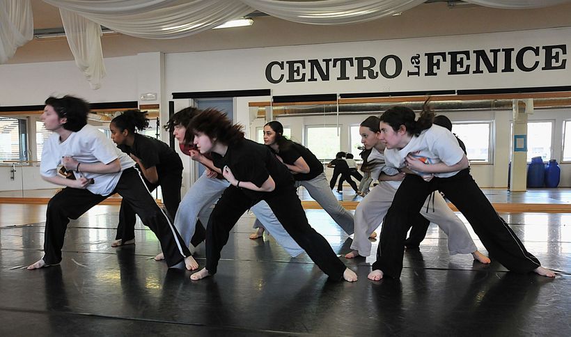 Persone che provano una posa di danza in una luminosa sala al coperto con una grande insegna 