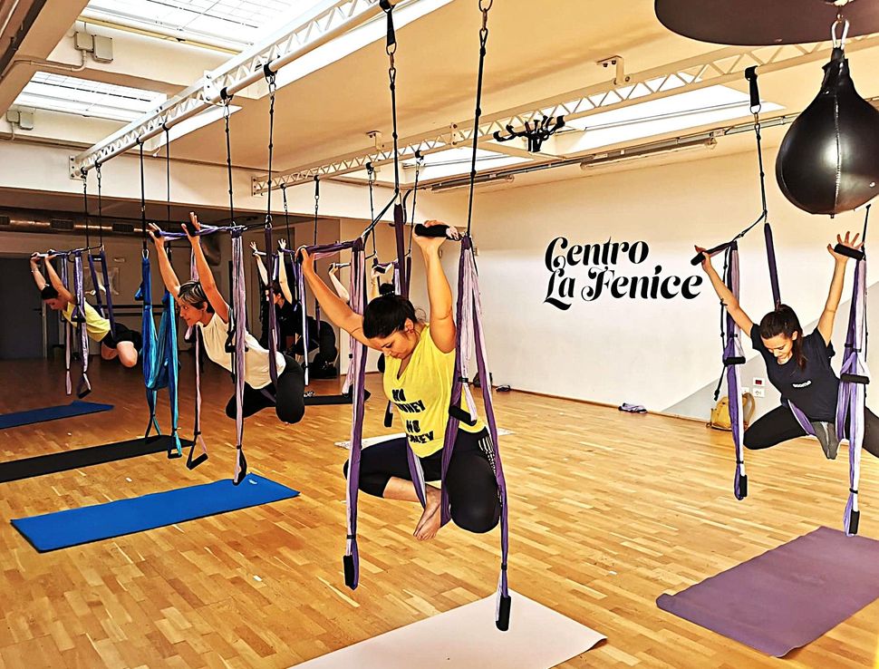 Lezione di Pilates sui reformer in uno studio luminoso, con tre persone che si allenano in sincronia.