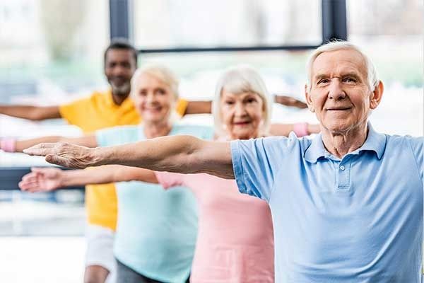 Persone che allungano le braccia in avanti in una luminosa lezione di fitness
