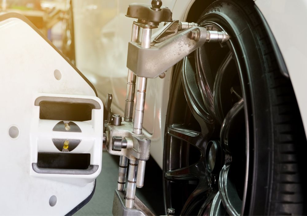 Close-up of a wheel alignment head clamped to a car’s alloy wheel