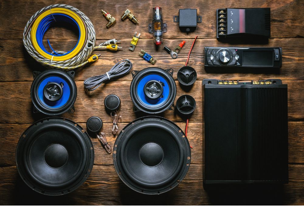 Car stereo, speakers, tweeters, amplifier and wiring laid out on a wooden table