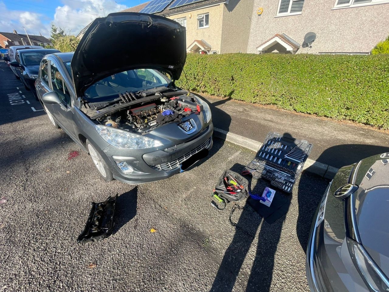 Peugeot with the bonnet open beside the kerb in Tilehurst, with the old rocker cover and tools laid out on the ground